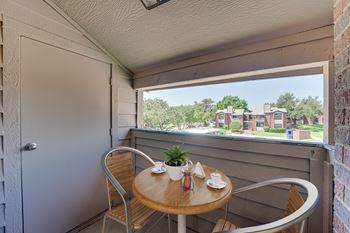 A small table with two chairs is set up on a balcony.
